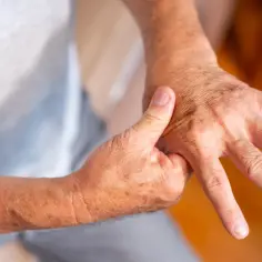 Osoba masuje dłoń, próbując złagodzić uciążliwy ból.