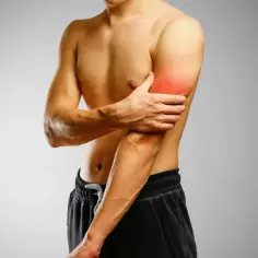 Mężczyzna trzyma się za bolący biceps, z zaczerwienionym obszarem na mięśniu.