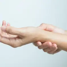 Dłoń trzymająca się za nadgarstek, sugerująca ból lub dyskomfort.