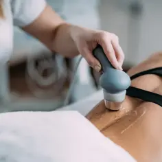 Fizjoterapeuta wykonuje zabieg ultradźwiękami na plecach pacjentki, stosując żel do lepszego przewodzenia.