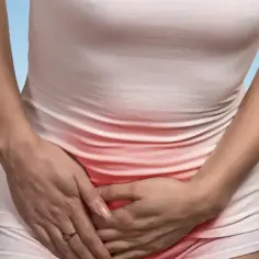 Kobieta trzymająca się za pachwinę, z zaczerwienieniem w okolicy bólu.