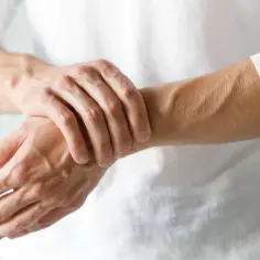 Mężczyzna masuje nadgarstek, odczuwając drętwienie rąk w nocy. Widoczne żyły i mięśnie przedramienia.