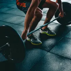 Mężczyzna podnosi ciężar, czuć napięty mięsień. Intensywny trening na siłowni.