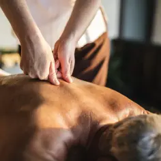 Dłonie terapeuty wykonują głęboki masaż kręgosłupa, przynosząc ulgę i relaks.