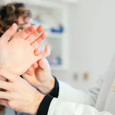 Lekarz od stawów bada dłoń pacjentki, szukając przyczyny bólu.
