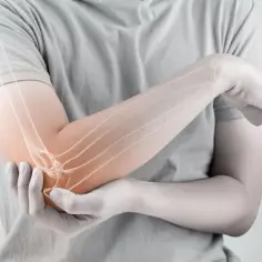 Anatomia stawu łokciowego z widocznymi kośćmi i podświetlonym obszarem bólu.
