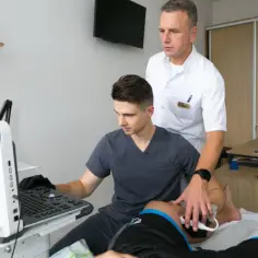 Lekarz sportowy z asystentem wykonuje badanie USG.